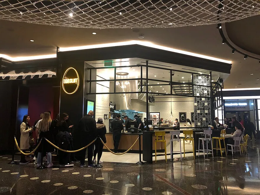 The Cosmopolitan 館内の Eggslut 店舗。黒いカウンターとネオンロゴ、待機列